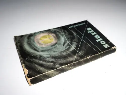A book on a white background. The book cover features a yellow circle in a dark gray background. Blue letters read "Solaris" and "Stanislaw Lem".